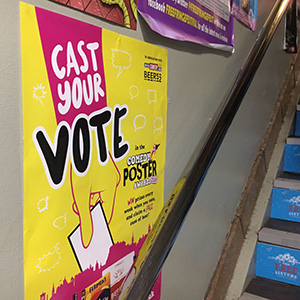 A poster promoting Comedy Poster Awards voting inside a Fringe venue