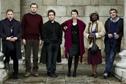 Rev.. Image shows from L to R: Archdeacon Robert (Simon McBurney), Nigel McCall (Miles Jupp), Rev Adam Smallbone (Tom Hollander), Alex Smallbone (Olivia Colman), Adoha Onyeka (Ellen Thomas), Colin Lambert (Steve Evets). Copyright: Big Talk Productions