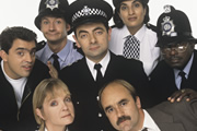 The Thin Blue Line. Image shows from L to R: D.C. Kray (Kevin Allen), P.C. Goody (James Dreyfus), Sergeant Dawkins (Serena Evans), Inspector Fowler (Rowan Atkinson), D.I. Grim (David Haig), P.C. Habib (Mina Anwar), P.C. Gladstone (Rudolph Walker). Copyright: Tiger Aspect Productions