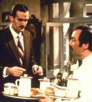 Fawlty Towers. Image shows from L to R: Basil Fawlty (John Cleese), Manuel (Andrew Sachs). Copyright: BBC