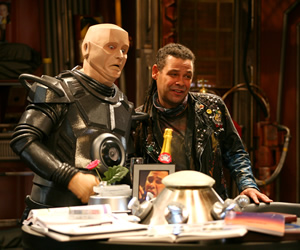 Red Dwarf. Image shows from L to R: Kryten (Robert Llewellyn), Lister (Craig Charles). Copyright: Grant Naylor Productions / BBC