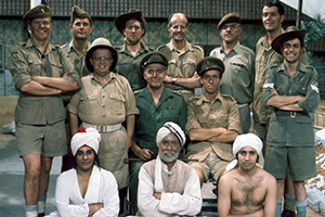 It Ain't Half Hot Mum. Image shows from L to R: Gunner 'Atlas' MacKintosh (Stuart McGugan), Gunner 'Nobby' Clark (Kenneth MacDonald), Char Wallah Muhammed (Dino Shafeek), Gunner 'Lofty' Sugden (Don Estelle), Gunner 'Nosher' Evans (Mike Kinsey), Colonel Charles Reynolds (Donald Hewlett), Rangi Ram (Michael Bates), Gunner 'Paderewski' Graham (John Clegg), Captain Jonathan Ashwood (Michael Knowles), BSM Geoffrey 'Shut Up' Williams (Windsor Davies), Punka Wallah Rumzan (Babar Bhatti), Gunner 'Parky' Parkin (Christopher Mitchell), Bombardier 'Gloria' Beaumont (Melvyn Hayes). Copyright: BBC