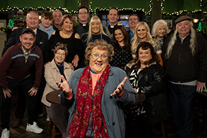 Mrs. Brown's Boys. Image shows left to right: Buster Brady (Danny O'Carroll), Dr Flynn (Derek Reddin), Bono Brown (Jamie O'Carroll), Mark Brown (Pat Shields), Winnie McGoogan (Eilish O'Carroll), Sharon McGoogan (Fiona Gibney), Trevor Brown (Martin Delany), Cathy Brown (Jennifer Gibney), Agnes Brown (Brendan O'Carroll), Father Damien (Conor Moloney), Maria Nicholson / Brown (Fiona O'Carroll), Dermot Brown (Paddy Houlihan), Betty Brown (Amanda Woods), Birdie (June Rodgers), Hillary Nicholson (Susie Blake), Grandad Brown (Dermot O'Neill). Credit: BBC