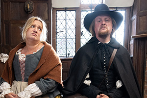 The Witchfinder. Image shows from L to R: Thomasine Gooch (Daisy May Cooper), Gideon Bannister (Tim Key)