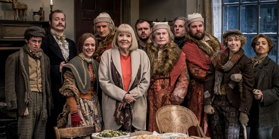 A Christmas Carol Goes Wrong. Image shows from L to R: Dennis / Bob Cratchit / Priest / Pallbearer (Jonathan Sayer), Jonathan / Marley / Topper / Businessman (Greg Tannahill), Sandra / Collector / Frances / Belle / Mrs. Cratchit / Olivia (Charlie Russell), Chris / Scrooge (Henry Shields), Aunt Diana / Narrator (Diana Rigg), Trevor (Chris Leask), Scrooge & Himself (Derek Jacobi), Max / Young Scrooge / Christmas Present / Collector / Undertaker (Dave Hearn), Robert / Bugsworth / Scrooge / Tiny Tim / Yet To Come / Pallbearer (Henry Lewis), Lucy / Tiny Tim (Ellie Morris), Annie / Frances / Christmas Past / Businessman (Nancy Zamit). Copyright: BBC