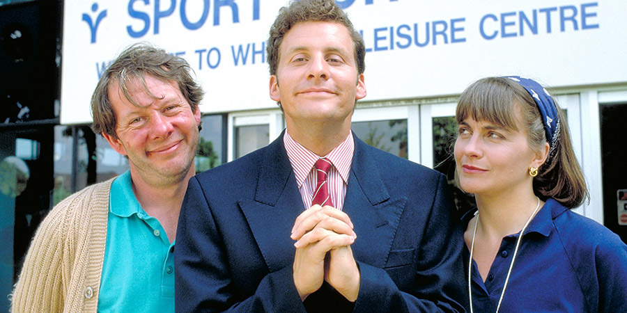 The Brittas Empire. Image shows from L to R: Colin Wetherby (Mike Burns), Gordon Brittas (Chris Barrie), Laura Lancing (Julia St. John). Copyright: BBC