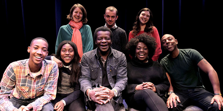 What Does The K Stand For?. Image shows from L to R: Young Stephen (Shaquille Ali-Yebuah), Stephanie Amos (Fatou Sohna), Miss Collins (Gemma Whelan), Stephen K Amos, PE Teacher (Harry Jardine), Fanni (Emerald O'Hanrahan), Virginia Amos (Ellen Thomas), Vincent Amos (Don Gilet). Copyright: BBC