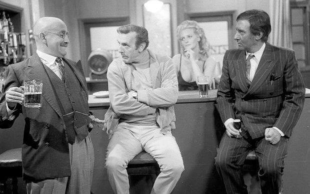 Till Death Us Do Part. Image shows left to right: Alf Garnett (Warren Mitchell), Arthur Blenkinsopp (Eric Sykes), Barmaid (Lorna Wilde), Kevin O'Grady (Spike Milligan). Credit: BBC