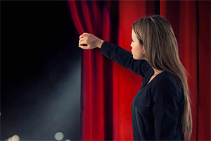 Woman looking out from behind a curtain