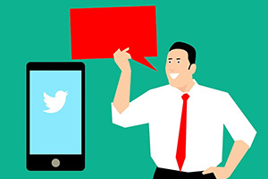 Man holding a speech bubble near a phone with Twitter logo on