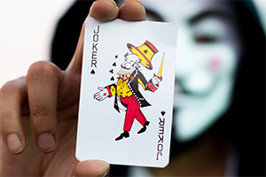 A masked person holding a Joker card