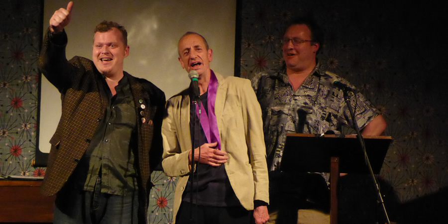 Arthur Smith picking up the Bath Plug Award 2019. Image shows from L to R: Jem Roberts, Arthur Smith, Nick Steel. Copyright: Alan Cassé