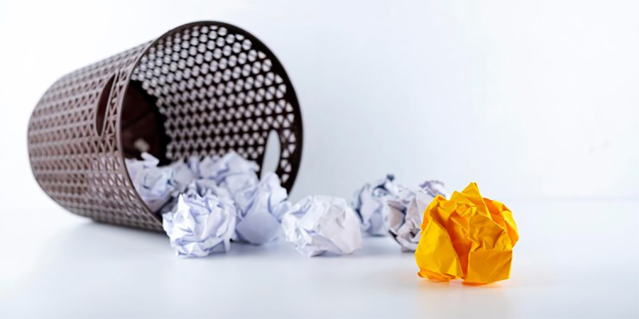 Crumpled paper spilling out a bin