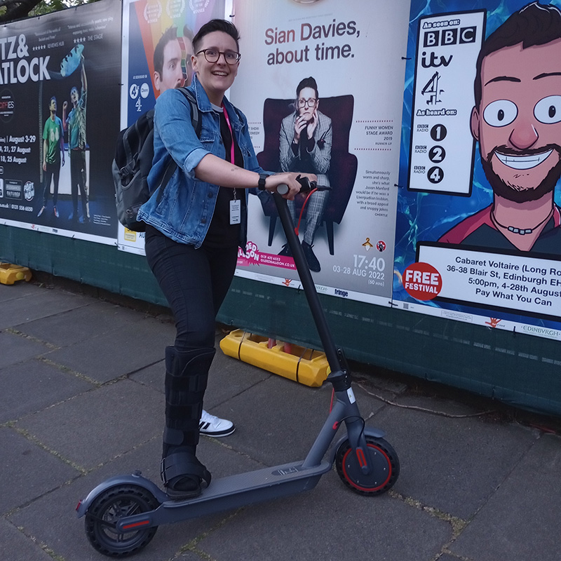 Sian Davies with her scooter, in front of a poster for her show. Sian Davies