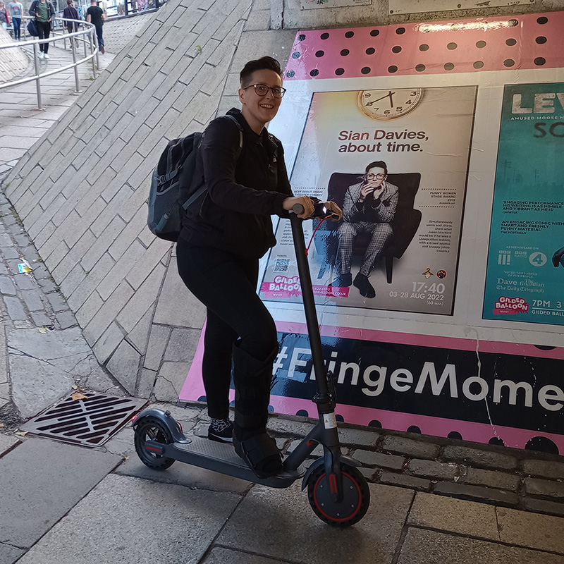 Sian Davies on her scooter, in front of a poster for her show in the Potterrow underpass. Sian Davies